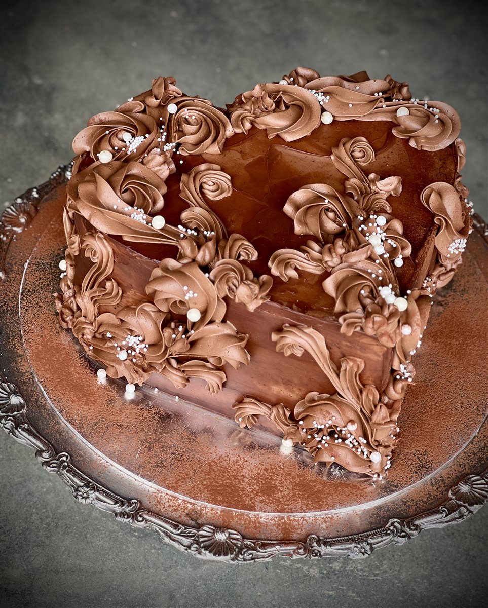 Heart-shaped dark chocolate ganache cake with baroque piped scrollwork