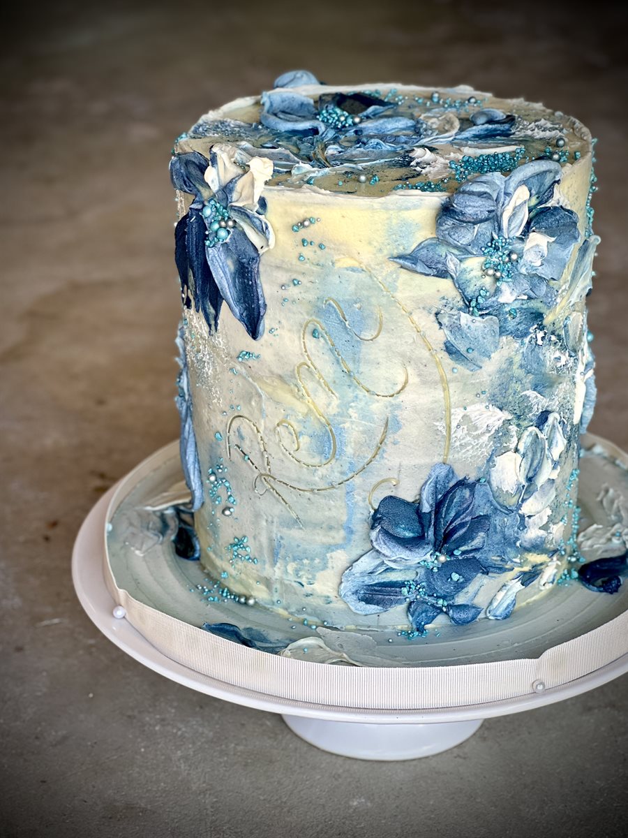 Tall single-tier celebration cake with a moody blue and silver palette-knife textured finish, scattered with deep navy and silver-leaf florals