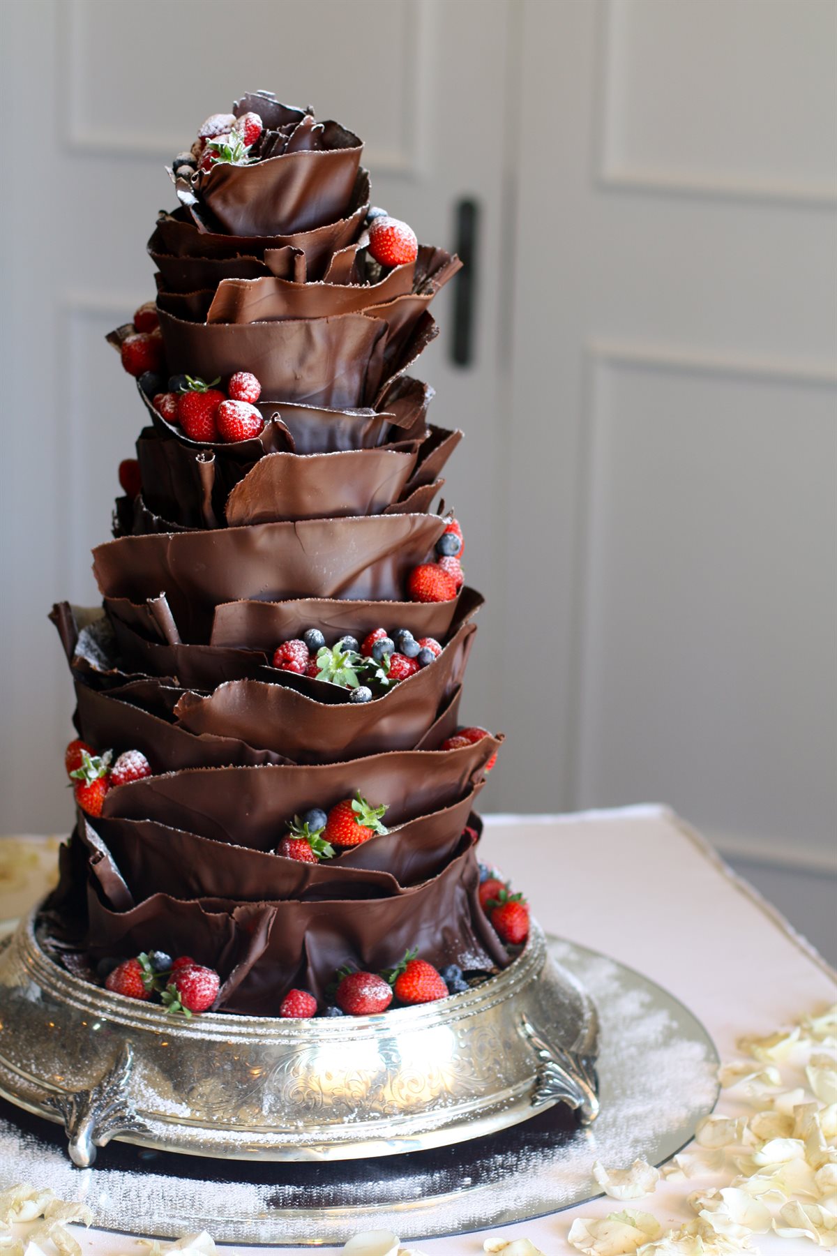 Couverture chocolate petal wedding cake with mixed berries and icing sugar