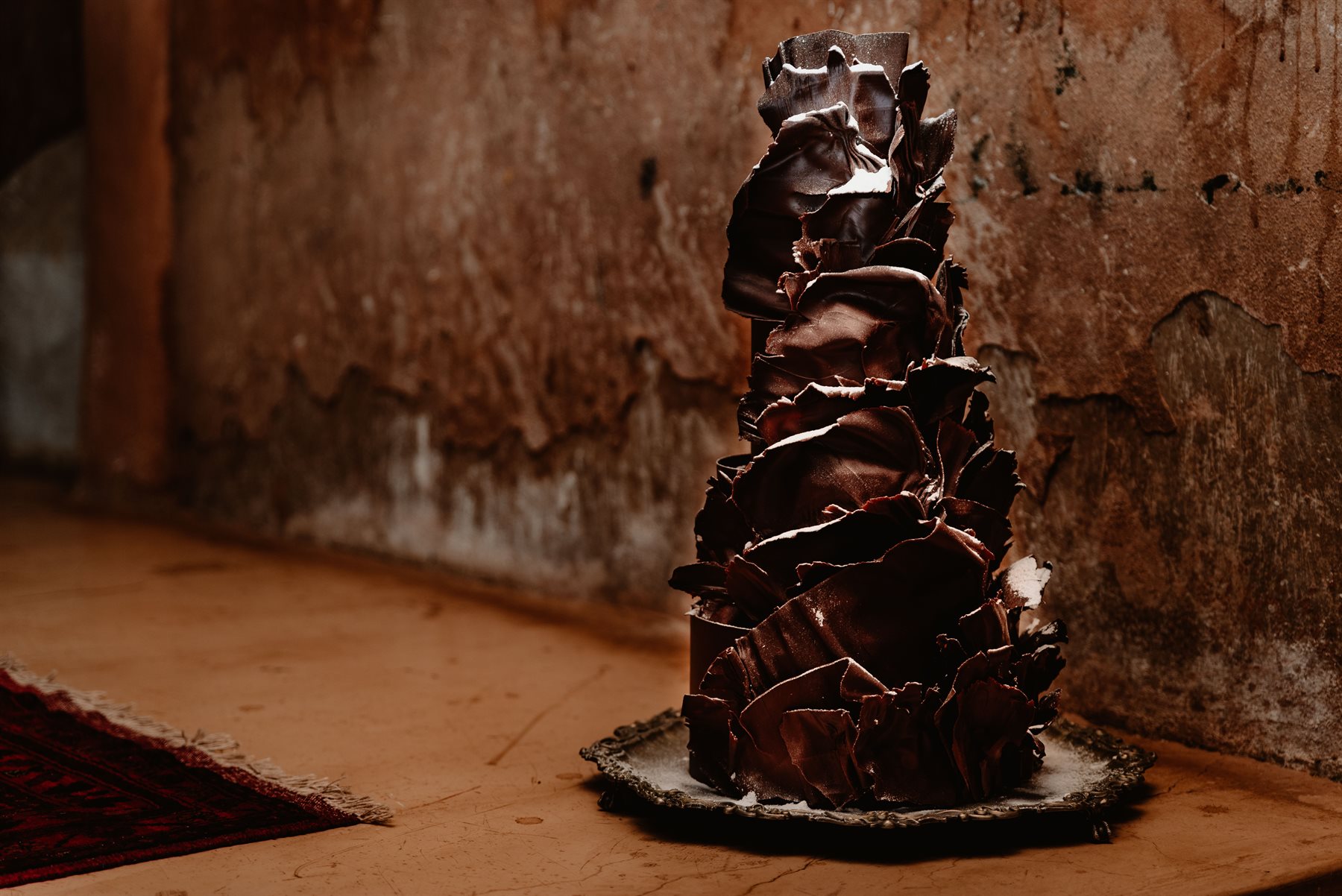 Dark chocolate sculptural wedding cake in moody industrial venue