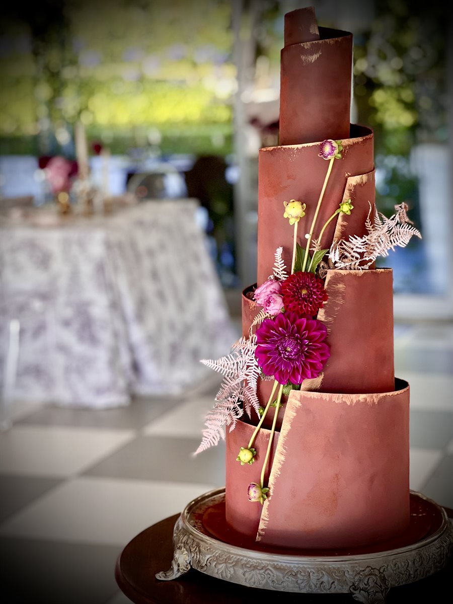 Four-tier gold edged sculpted couverture chocolate cake with magenta dahlias