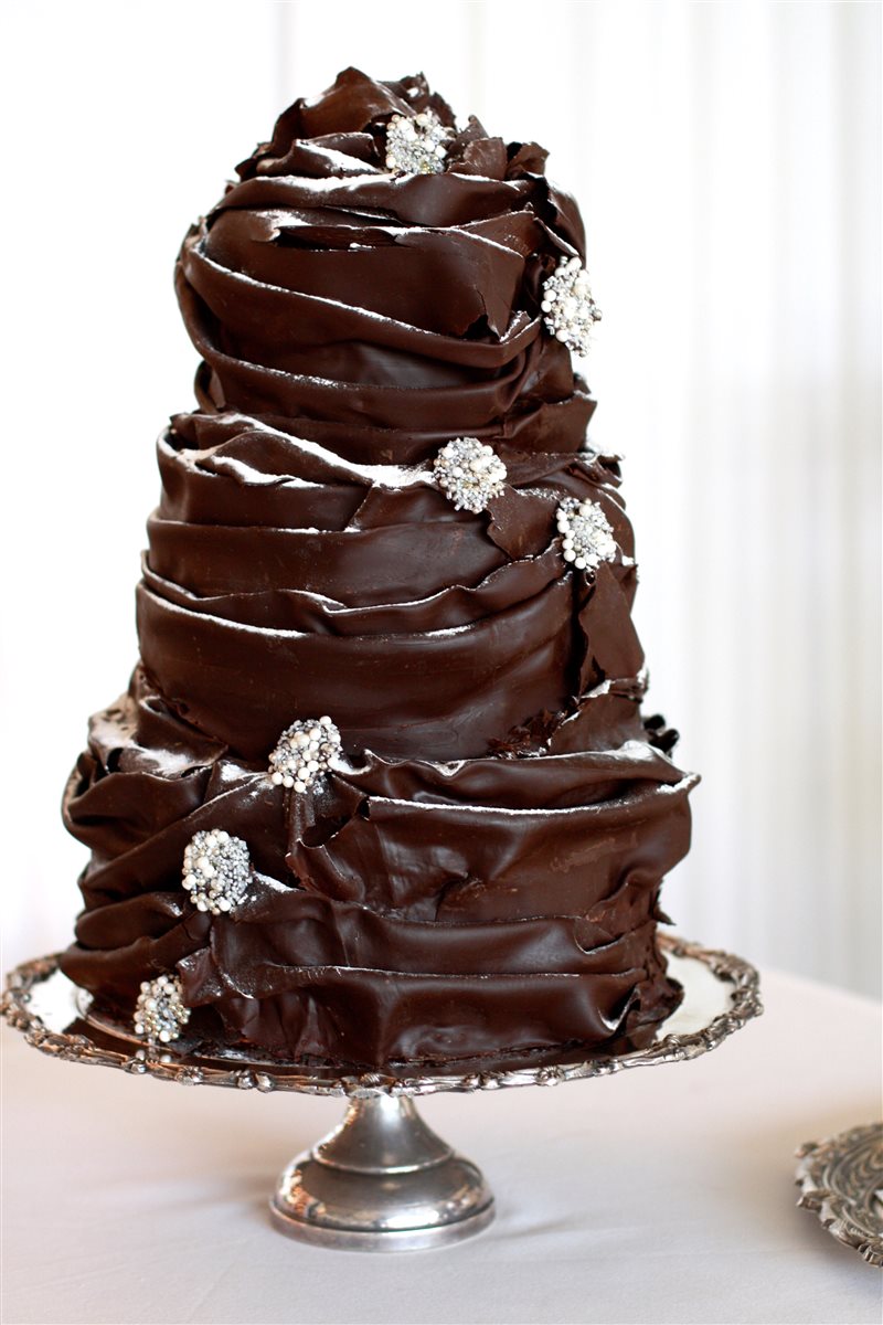 Conical multi-tier dark chocolate swirling ruffle cake with silver jewel brooch accents