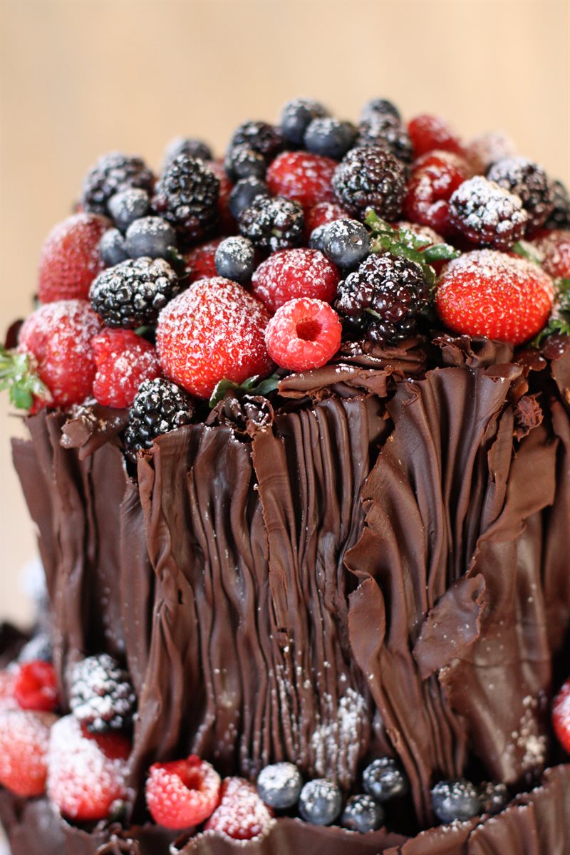 Detail of chocolate bark cascading into sugar-dusted mixed berries