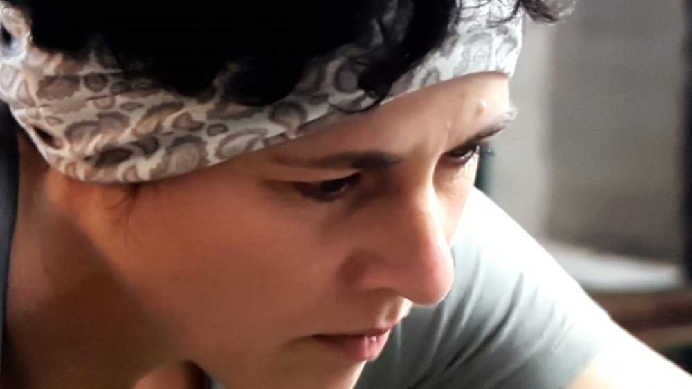 Kanya Hunt in her kitchen, headwrap on, focused on her craft