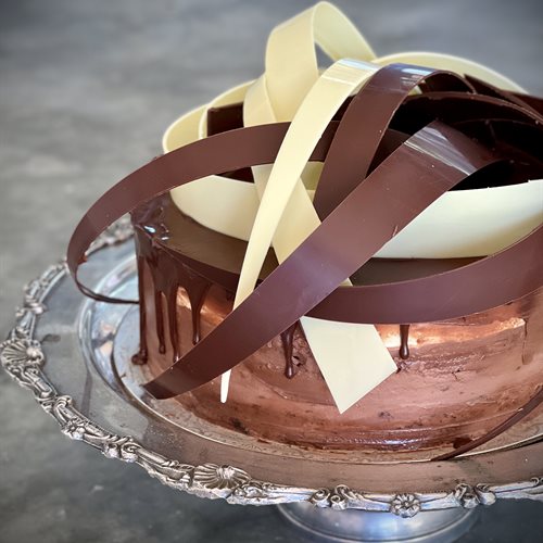 Interlocking dark and white chocolate ribbons crowning a ganache drip cake