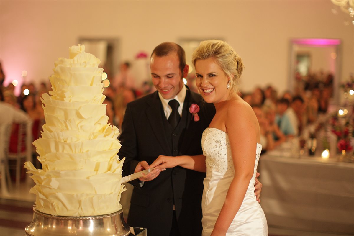Couple cutting their couverture chocolate wedding cake in a grand ballroom venue