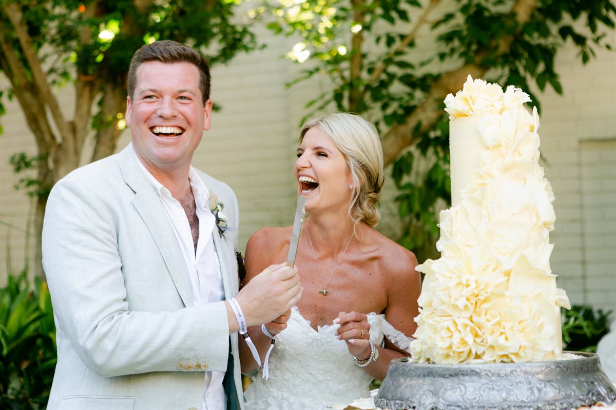 Charlotte and Harry cutting their white chocolate couverture cake in an elegant garden