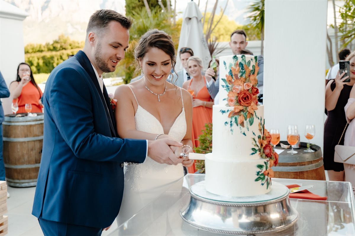 Wesley and Endri cutting their hand-painted botanical couverture cake at a Winelands vineyard