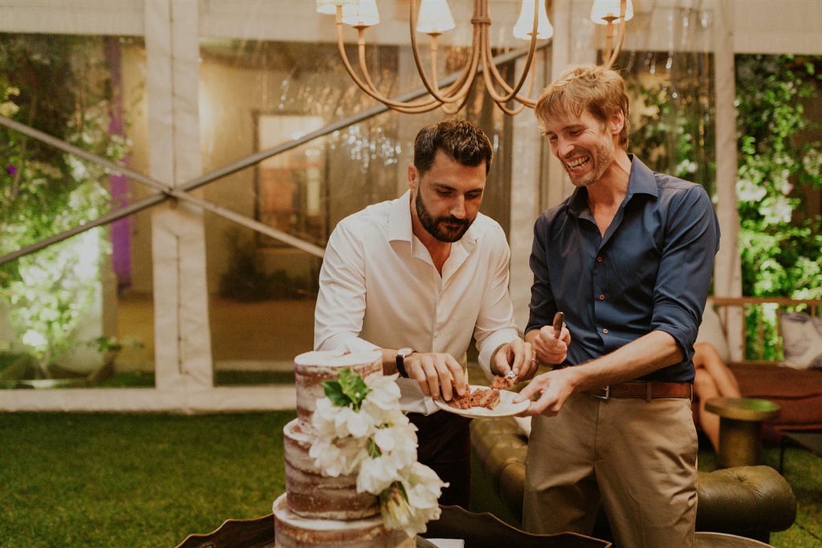 Couple smiling as they share couverture chocolate cake in a lush garden wedding setting