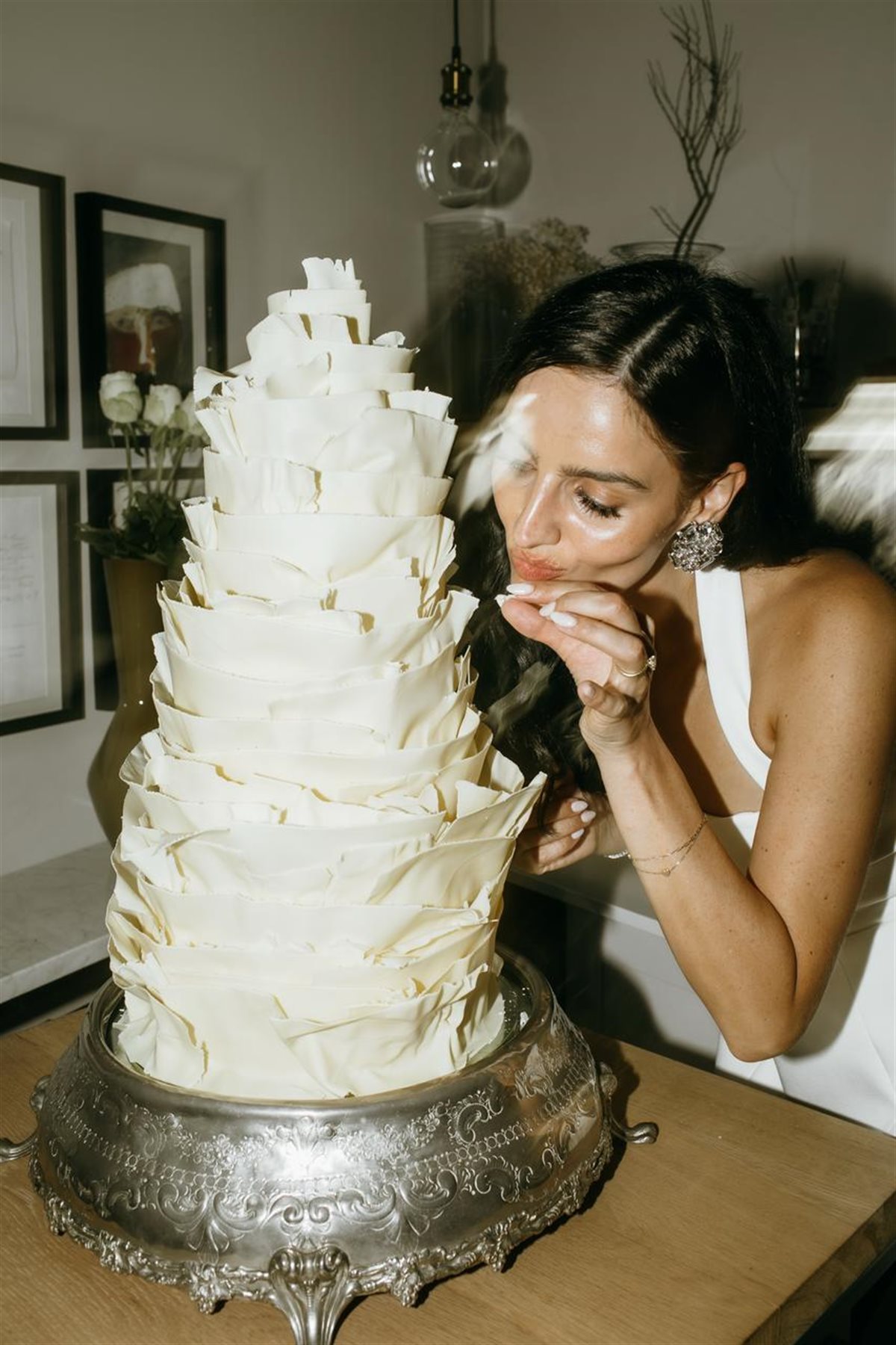 Bride posing with a sculptural white couverture chocolate cake in a modern editorial shoot