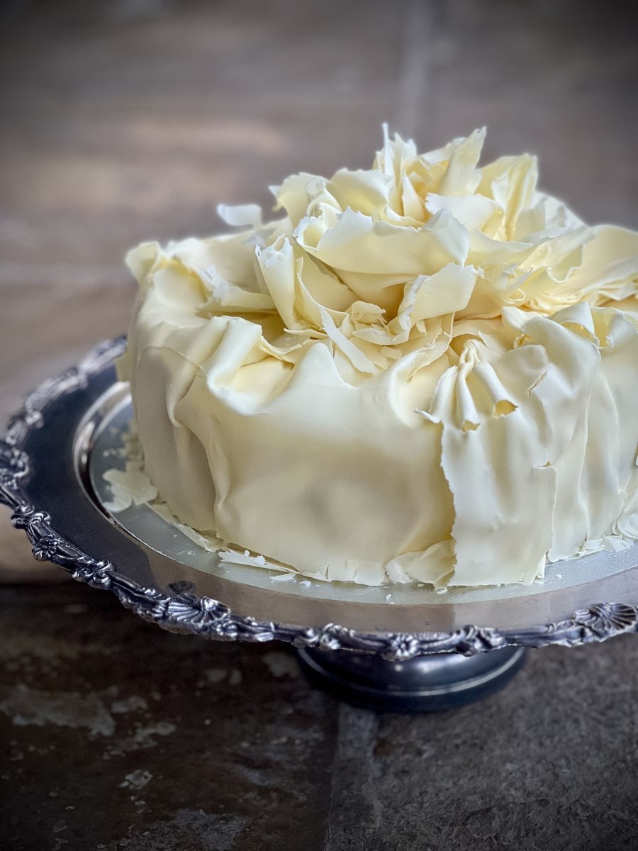 White couverture cake encased in large ivory white chocolate petals and shards