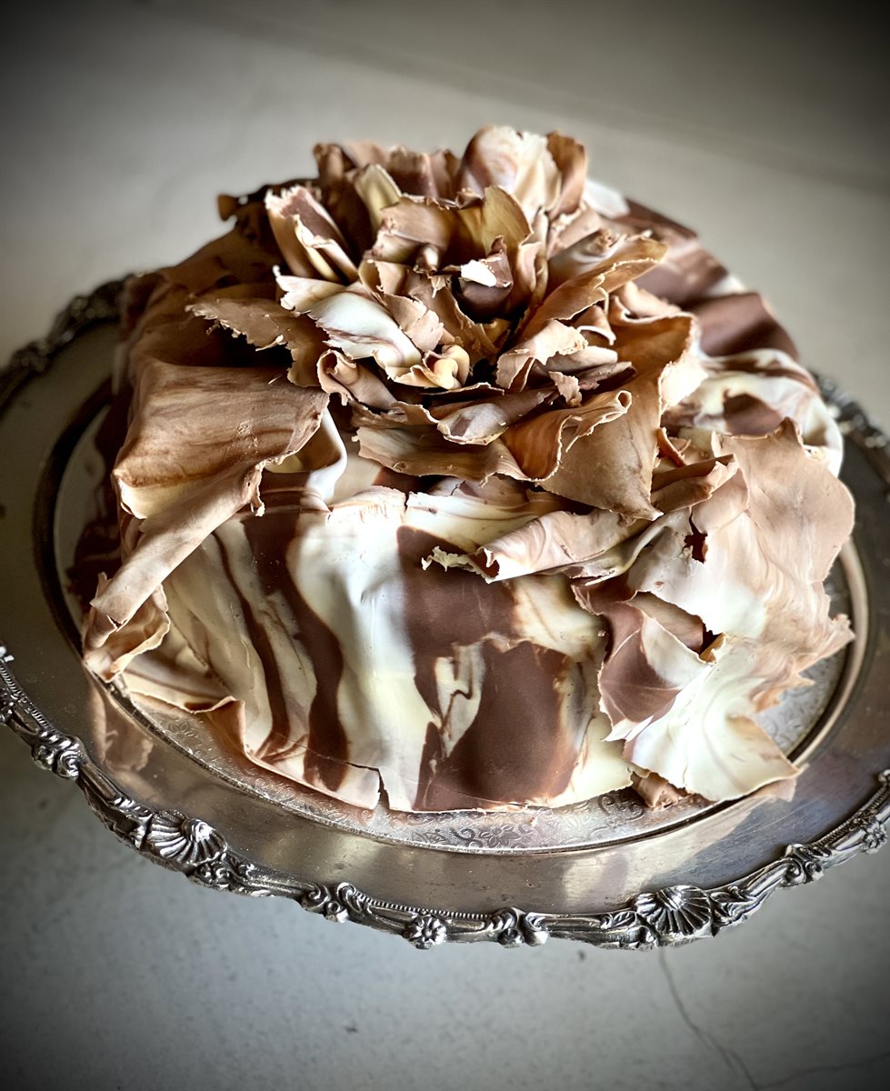 Dark and white marble-swirl couverture shards with a large bloom of mixed chocolate petals on top