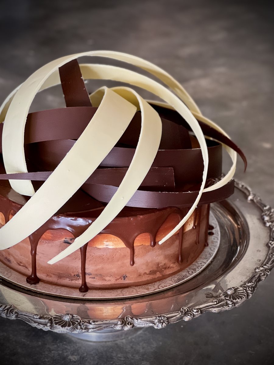 Dark chocolate drip cake with interlocking dark and white chocolate ribbon spirals rising overhead