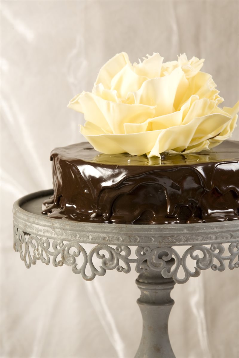 Dark chocolate ganache-poured cake topped with a large sculptured ivory white couverture rose