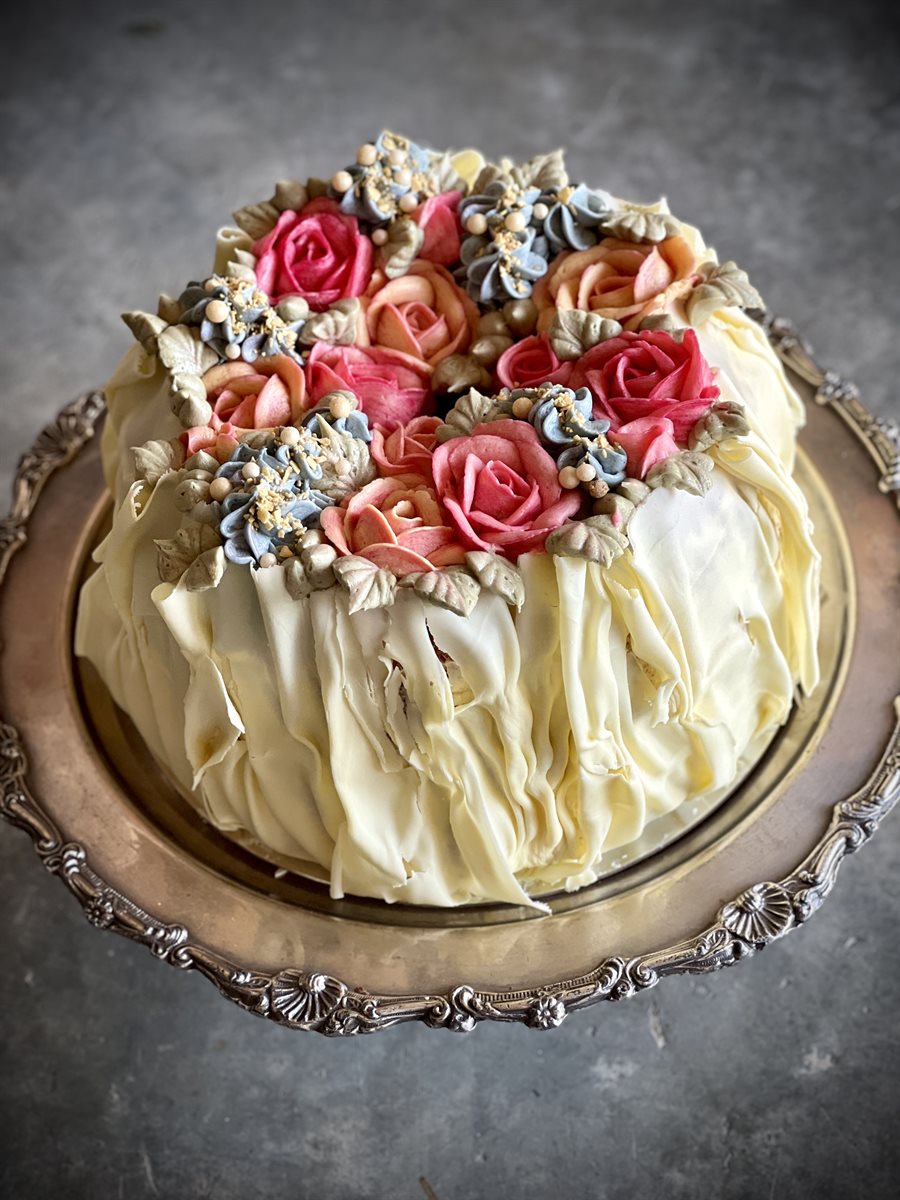 Chiffon cake with white chocolate ruffled sides and a wreath of pink and coral roses
