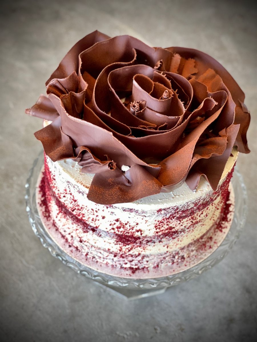 Semi-naked red velvet cake with crimson crumbs and a large sculpted dark couverture chocolate rose