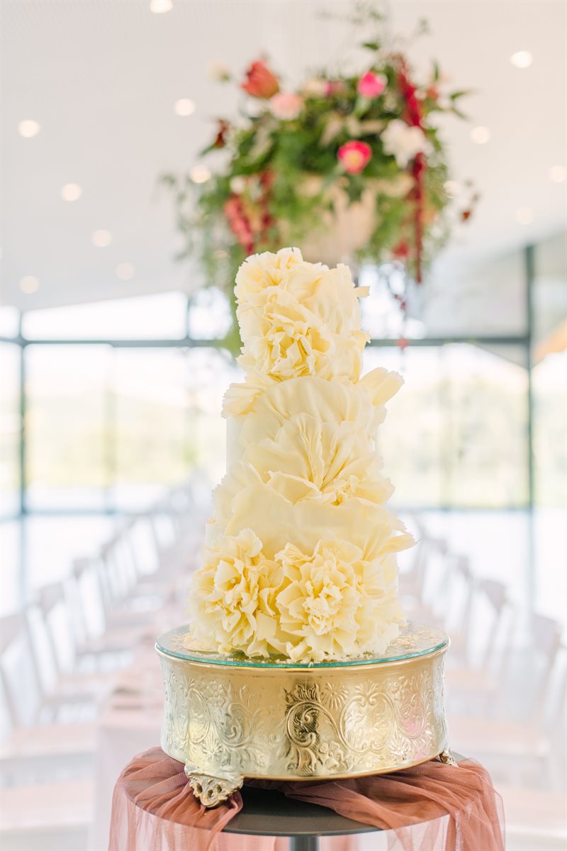 Fluffy white couverture peony-tier cake in bright modern venue